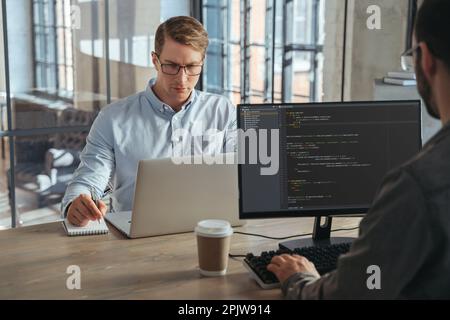 Due specialisti IT collaborano in ufficio, lavorando su nuovi prodotti, analizzando dati, programmando nuovi software Foto Stock