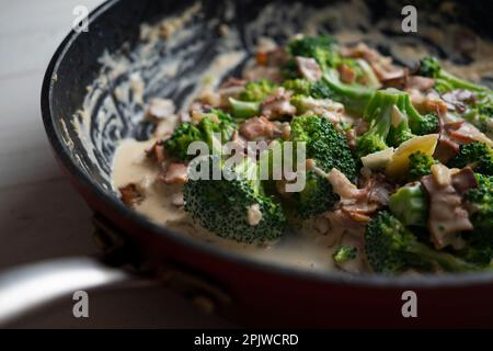 Broccoli cotti con crema di carbonara italiana con pancetta. Foto Stock