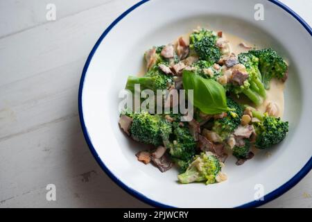 Broccoli cotti con crema di carbonara italiana con pancetta. Foto Stock