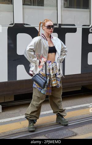 MILANO, ITALIA - 25 FEBBRAIO 2023: Donna con bomber d'argento e pantaloni cargo beige prima della sfilata di moda Dolce e Gabbana, Milano Fashion Week s Foto Stock
