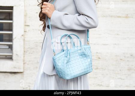 MILANO, ITALIA - 25 FEBBRAIO 2023: Donna con borsa in pelle azzurro, giacca grigia e gonna d'argento prima della sfilata Missoni, Milano Fashion Week stre Foto Stock