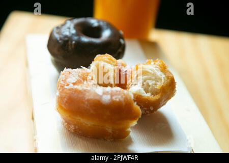 Una ciambella mezza mangiata è su un foglio bianco Foto Stock