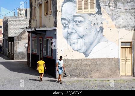 Persone che camminano sulla strada da un edificio con grande muro Cesaria Evora murale sulla casa, Ribeira Grande, Capo Verde Foto Stock