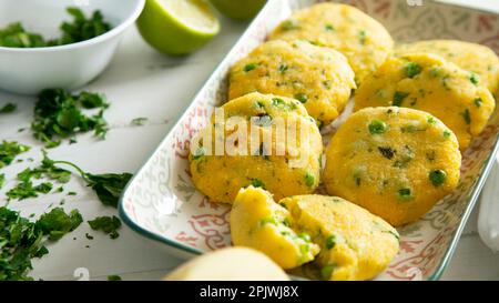 Torte salate fritte di polenta con piselli. Foto Stock