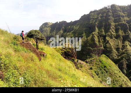 Donna turistica in un viaggio escursionistico sulle montagne di Santo Antao, in piedi su una roccia e guardando le belle montagne, Cabo verde Foto Stock