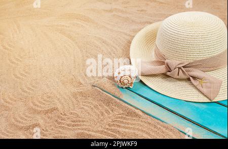 Cappello da sole con conchiglia e stelle marine su una tavola di legno blu sulla spiaggia sabbiosa. Estate, vacanza, turismo in paese caldo Foto Stock