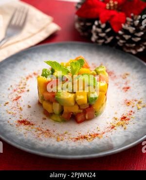 Tartare di avocado, mango e pomodoro su un tavolo con decorazioni natalizie. Foto Stock