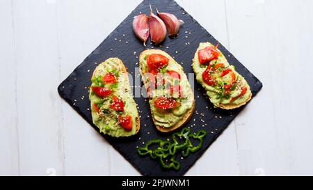 Due toast di pane biologico con avocado e pomodori ciliegini. Foto Stock