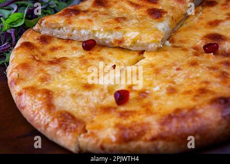 Una tradizionale parabola georgiana di Khachapuri Megreliani con erbe e verdi fresche Foto Stock