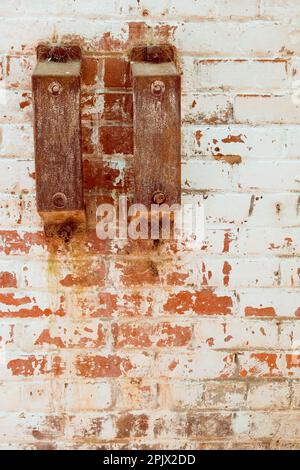 Staffe in ferro arrugginito con ragnatela su parete in mattoni bianchi. Foto Stock