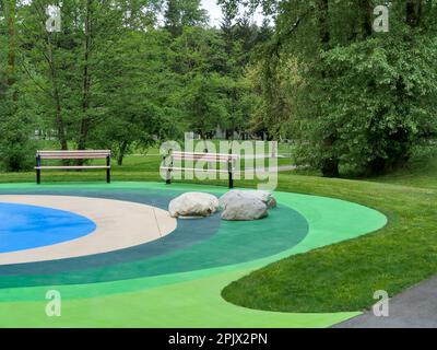 Area ricreativa in un parco con due panchine su terreno colorato Foto Stock