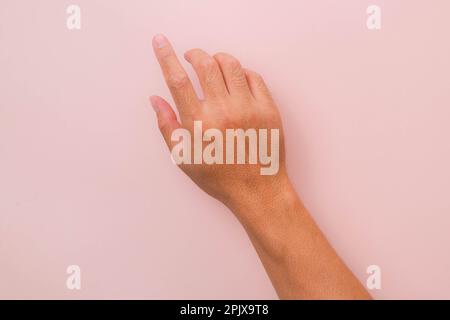 Mano maschile che tocca con un dito isolato su sfondo rosa. Mani per azionare il touch panel. Foto Stock