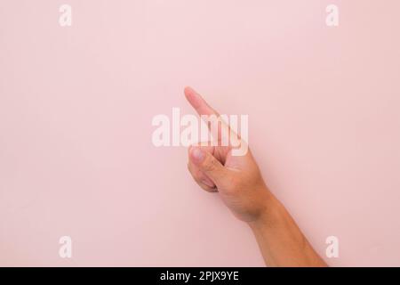 Primo piano della mano maschile che punta isolata su sfondo rosa. Mano dell'uomo che tocca o indica qualcosa Foto Stock