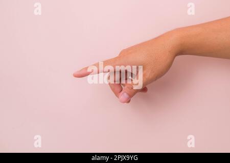 Primo piano della mano maschile che punta isolata su sfondo rosa. Mano dell'uomo che tocca o indica qualcosa Foto Stock