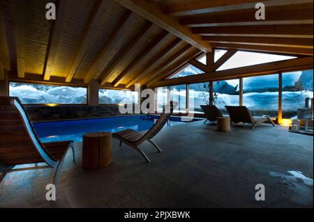 La piscina riscaldata di fronte alla neve dell'hotel Sant'Orso nel comune di Cogne, ai piedi del gruppo Gran Paradiso. Valle d'Aosta, Italia, Euro Foto Stock