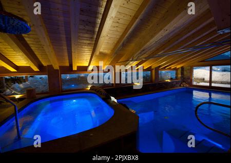 La piscina riscaldata di fronte alla neve dell'hotel Sant'Orso nel comune di Cogne, ai piedi del gruppo Gran Paradiso. Valle d'Aosta, Italia, Euro Foto Stock