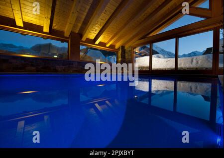 La piscina riscaldata di fronte alla neve dell'hotel Sant'Orso nel comune di Cogne, ai piedi del gruppo Gran Paradiso. Valle d'Aosta, Italia, Euro Foto Stock