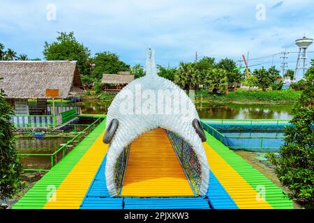 La splendida vista del tunnel assomiglia a pesci grandi fatti da molte bottiglie di plastica chiara usate sul ponte pedonale sopra il fiume. Utilizzando vecchi flaconi di plastica t Foto Stock