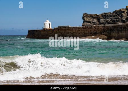 Vista mare delle onde e del Porto Muro con il rifugio Look out e Shoreline si gonfiano all'inizio dell'estate. Portreath Beach, Cornovaglia. Foto Stock