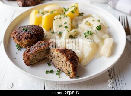 Cucina tradizionale tedesca con polpette di maiale o frikadellen. Servito con kohlrabi cotti e salsa di besciamella e patate bollite su un piatto Foto Stock