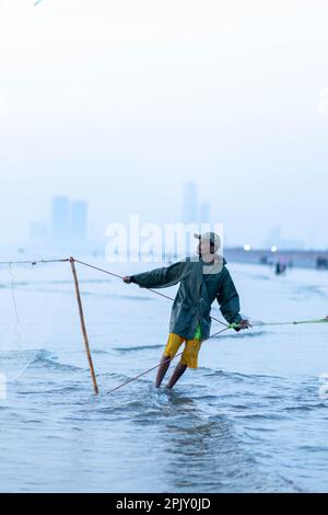 karachi pakistan 2021, un pescatore che tira la rete di pesca per catturare i pesci, alla vista del mare in ora di sera. Foto Stock