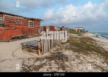 Diverse cabine e capanne abbandonate, tra cui una costruita con vecchi pallet in legno, fiancheggiano la spiaggia di Rincon di Aruba vicino a San Nicolas. Foto Stock