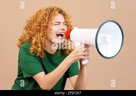 Donna dai capelli ricci arrabbiata urla sopra un altoparlante Foto Stock