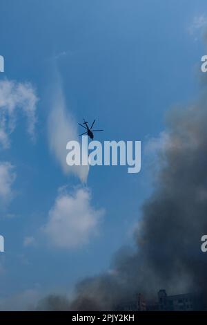 Elicotteri dall'aeronautica militare del Bangladesh che cadono acqua sul fuoco. All'alba del 4 aprile 2023, un incendio di massa scoppiò a Bangabazar, uno dei più grandi mercati di stoffa a Dhaka, Bangladesh. Secondo quanto riferito, l'incendio è iniziato intorno alle 6:00 in uno dei negozi e si è rapidamente diffuso al resto del mercato. Il fuoco si è acceso per quasi 7 ore prima di essere messo sotto controllo. L'incendio ha causato gravi danni al mercato, con la maggior parte dei negozi e delle bancarelle eviscerate dalle fiamme. (Foto di Rizwan Hasan/Pacific Press) Foto Stock