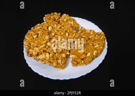 tradizionale gazak dolce indiano in piatto bianco con fondo nero Foto Stock