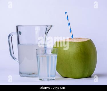 Acqua di cocco. Tazza, vaso e cocco verde su sfondo bianco. Foto Stock