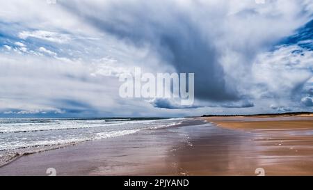 Nuvole pesanti sulla spiaggia di Brora con riflessi in sane bagnate Foto Stock