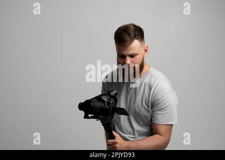 Regista professionale con una fotocamera dslr su stabilizzatore a 3 assi. Concetto di filmmaking, videografia, hobby e creatività. Foto Stock