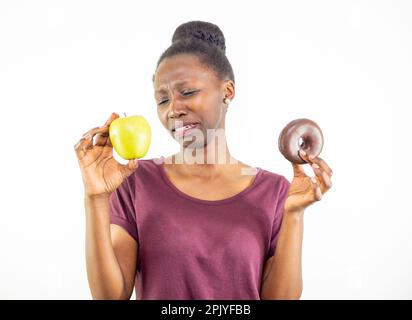 Giovane donna che sceglie tra cibo sano e cibo spazzatura isolato su sfondo bianco Foto Stock