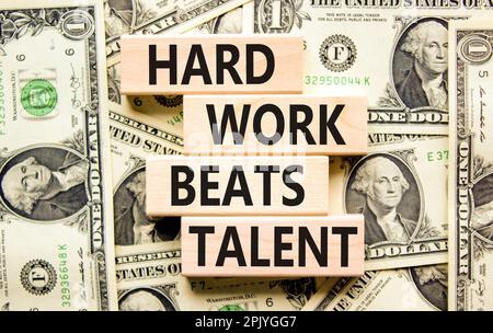 Il duro lavoro batte il simbolo del talento. Concetto parole duro lavoro batte talento su blocco di legno. Sfondo bello da dollari fatture. Har motivazionale di affari Foto Stock