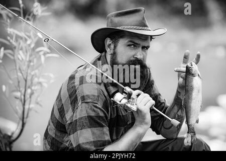 Ritratto dell'uomo in vacanza. Pesca sfondo. Avventure di pesca del mosca. Uomo vestito di pesca camicia con canna sul lago. Tempo del fine settimana. Pescatore uomo Foto Stock