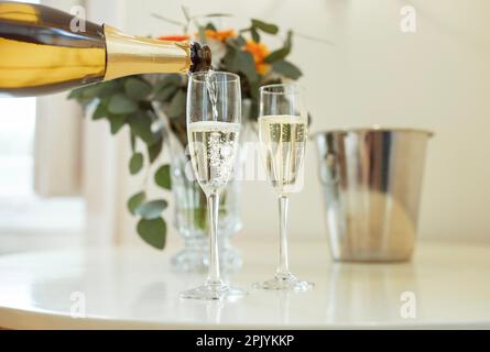 Primo piano di vino frizzante che si versa in bicchieri sul tavolo al coperto Foto Stock