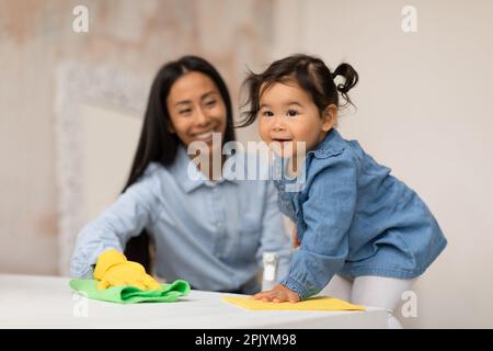 Madre giapponese e figlia bambino che fanno i lavori di casa insieme a casa Foto Stock