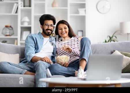 Felice coppia internazionale che guarda film sul computer portatile a casa Foto Stock