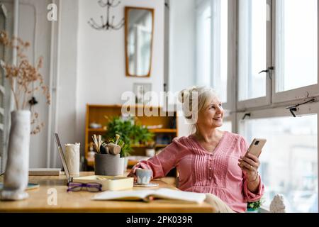 Sorridente donna senior utilizza lo smartphone Foto Stock
