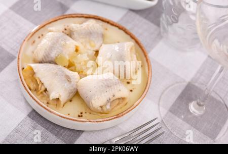Su piatto di tovaglia a scacchi con antipasto - involtini di filetto di aringa atlantica salata con cipolle Foto Stock