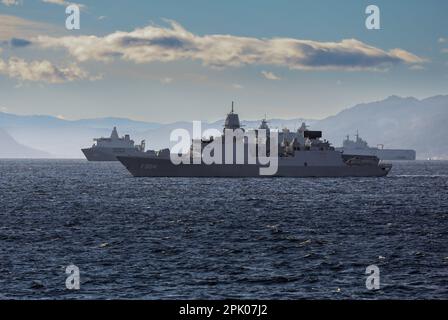 La fregata olandese HNLMS De Ruyter accompagna navi d'assalto anfibi in un fiordo norvegese durante gli esercizi della NATO. Foto Stock