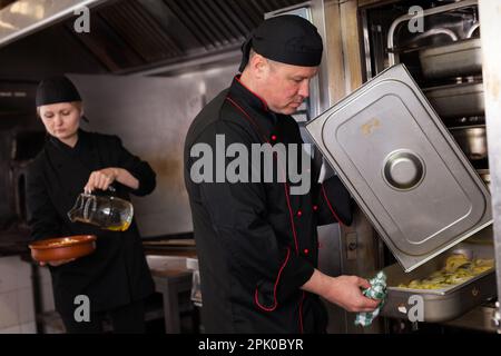 Chef preparandosi piatto fuori dal forno Foto Stock