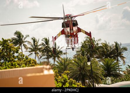 Hallandale Beach, Miami, Florida - 4 aprile 2023: Elicottero che solleva l'enorme Air-Condition Roof Top Centrale unità al tetto della cima del alto edificio Foto Stock