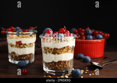 Delizioso parfait di yogurt con frutti di bosco freschi sul tavolo di legno Foto Stock