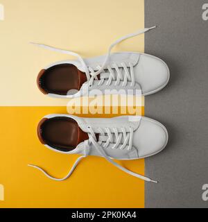 Paio di eleganti sneaker bianche su sfondo colorato, a posa piatta Foto Stock