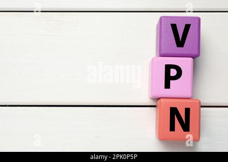 Cubi di colore con acronimo VPN su sfondo di legno bianco, piano. Spazio per il testo Foto Stock