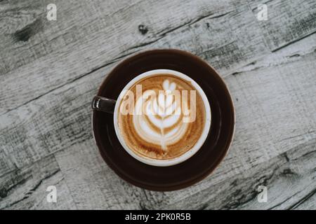 Piatto Lay o vista dall'alto shot di una tazza di caffè con belle latte Art su un tavolo di legno. Primo piano. Foto Stock