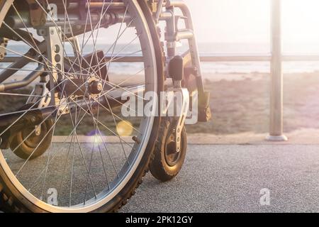 Una sedia a rotelle si trova sul lungomare senza persone Foto Stock