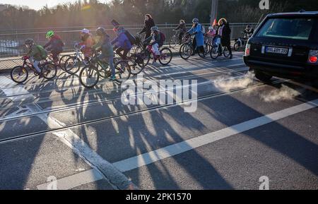 Halle, Germania. 28th Mar, 2023. Gli studenti, i genitori e i bambini del centro di cure diurne si fermano sul cosiddetto bus ciclabile di fronte al Burg Giebichenstein, attraversando la Saale durante l'ora di punta. In giorni selezionati, gli adulti cavalcano con i bambini e le scorte della polizia in un grande gruppo attraverso Halle lungo un percorso fisso per la scuola o l'asilo. Per salire sull'autobus, i passeggeri devono semplicemente attendere lungo il percorso. Con questa azione, anche i bambini e gli adulti vogliono lottare per una maggiore accettazione per i ciclisti sulle strade. Credit: Jan Woitas/dpa/Alamy Live News Foto Stock