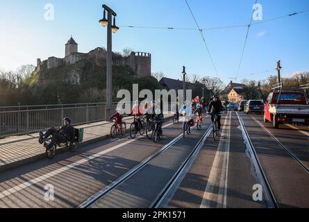 Halle, Germania. 28th Mar, 2023. Gli studenti, i genitori e i bambini del centro di cure diurne si fermano sul cosiddetto bus ciclabile di fronte al Burg Giebichenstein, attraversando la Saale durante l'ora di punta. In giorni selezionati, gli adulti cavalcano con i bambini e le scorte della polizia in un grande gruppo attraverso Halle lungo un percorso fisso per la scuola o l'asilo. Per salire sull'autobus, i passeggeri devono semplicemente attendere lungo il percorso. Con questa azione, anche i bambini e gli adulti vogliono lottare per una maggiore accettazione per i ciclisti sulle strade. Credit: Jan Woitas/dpa/Alamy Live News Foto Stock